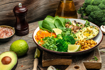 healthy vegan lunch bowl with Avocado, mushrooms, broccoli, spinach, chickpeas, pumpkin on a wooden background. vegetables salad. Top view