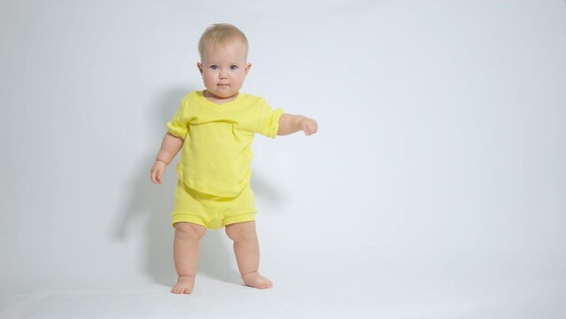 a baby standing on his feet examines his clothes