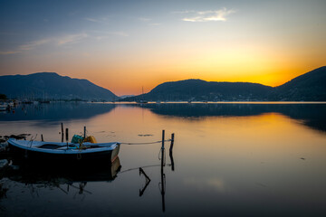 A long exposure of sunrise seascape with a small wooden boat in a bay.
