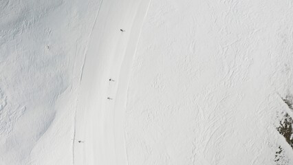 People snowboarding skiing at ski resort. Skiers, snowboarders riding snowy mountain slope. Outdoor winter sport activities. Aerial, top view