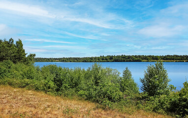 Beautiful dutch maas dunes landscape, blue lake water, green forest along hiking and cycle trail - Maasduinen NP, Reindersmeer, Netherlands