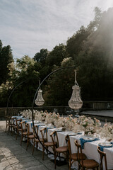 Lake Como, Italy, luxury destination wedding table setup and design. A table with wedding flowers, chandeliers, stationery, chairs 