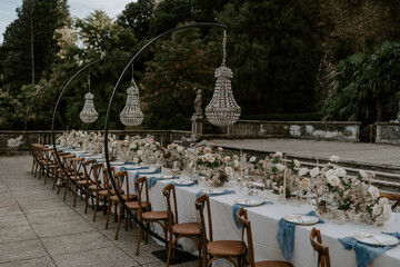Lake Como, Italy, luxury destination wedding table setup and design. A table with wedding flowers, chandeliers, stationery, chairs 