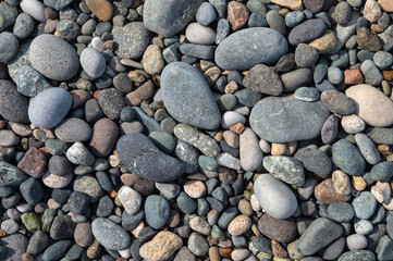 Fototapeta na wymiar Background of sea stones of a rounded shape. Colorful natural pebbles for texture patterned wallpaper. View from above.