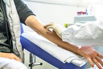 Details of a nurse hand looking for vein in arm of patient girl drawing blood sample for blood test in blood testing laboratory. - 618293991