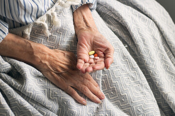 Old woman holding medicine and taking vitamins to heal. Colorful pills in old woman hand. Care for...