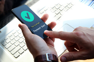 Businessman is  using his smartphone and laptop. Payment sent.