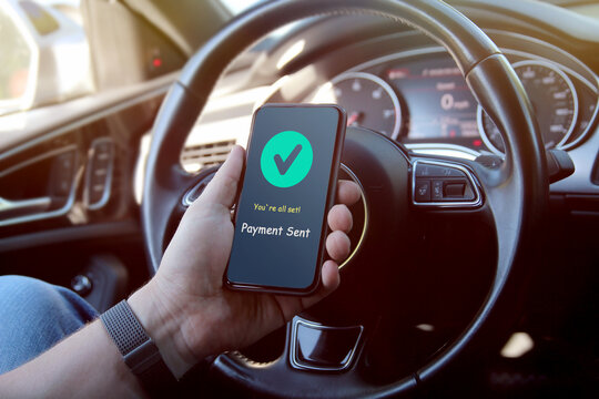 Man is paying online with mobile phone inside a car.