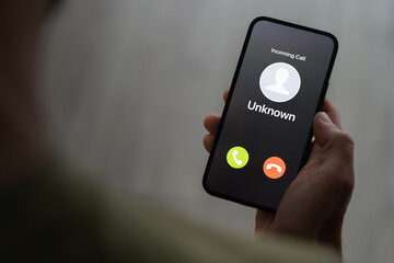 Scam call concept, person holding ringing phone with unknown caller, fraud attempt