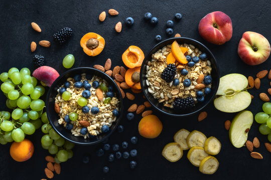 Two healthy breakfast bowl with ingredients granola fruits Greek yogurt and various berries on dark background top view. Weight loss, healthy lifestyle and eating concept