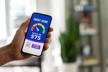 Person holding a smartphone with bad credit score meter on the screen