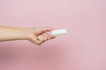 Drops bottle for eye or ear in hand on pink background. Pharmaceutical product. Copy space.