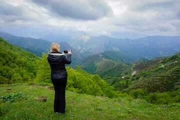 Fototapeta na wymiar Pretty young blonde woman contemplating the grandeur of the green landscape of the Picos de Europa in Asturias