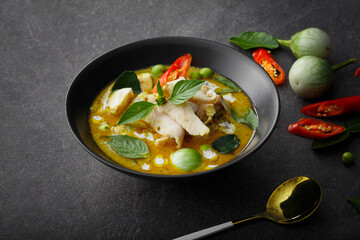 Exquisite Thai Cuisine: Green Curry Chicken, Infused with Aromatic Chili Paste and Creamy Sauce, Presented in a Black Bowl on a Textured Background