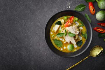 Exquisite Thai Cuisine: Green Curry Chicken, Infused with Aromatic Chili Paste and Creamy Sauce, Presented in a Black Bowl on a Textured Background