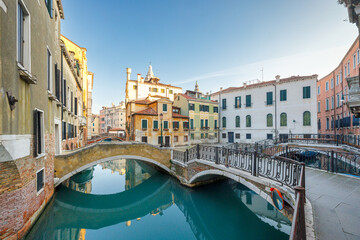 Fototapeta na wymiar Canal with stone bridges and historic buildings in Venice, Italy, Europe.