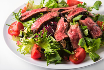 Pieces of beef with fresh lettuce and cherry tomatoes, dressed with olive oil and balsamic cream.