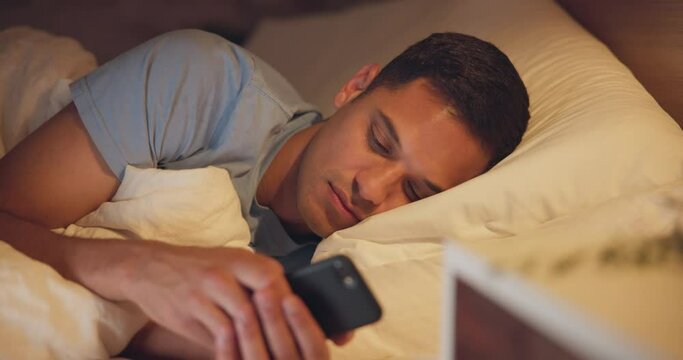 Insomnia, night and man with a smartphone, bedroom and tired with fatigue, addiction and sleepless. Male person, mobile app or guy with a cellphone, evening or end depression with rest or anxious