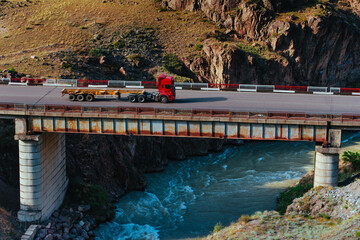 Fototapeta na wymiar Road bridge with truck over the river in the mountains