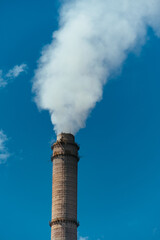 Pipe with dense smoke on blue sky background