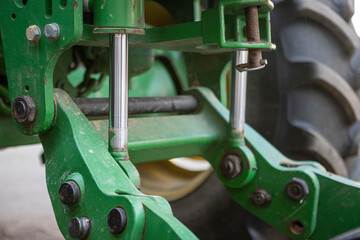 Shiny hydraulic cylinders of a used green agricultural machine. Detailed view, slightly dirty and...