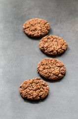 Chocolate cookies with oatmeal, chocolate chips and hazelnuts. Dark grey background.
