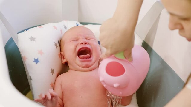 A newborn baby crying inconsolably and refused to have a bath. Unhappy kid takes military procedures for the first time. The concept of children and hygiene