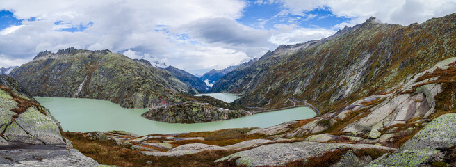 Panoramic photo of a desert road among milky green lakes in the Swiss Alps in autumn. Beautiful landscape shot of mountains in Switzerland