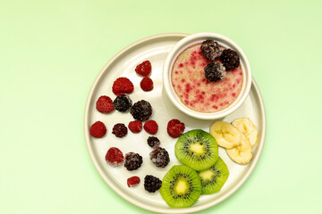 Sweet ice cream yogurt with frozen banana kiwi fruits, blackberry, raspberry berries. Cold fresh summer homemade dessert food on gray plate