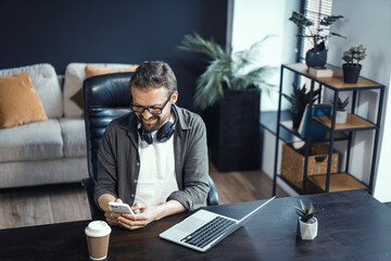 Fototapeta na wymiar Concept of working from home, featuring mid-aged man working on laptop. Man seen in comfortable home office environment, highlighting convenience and benefits of working from comfort of one's own