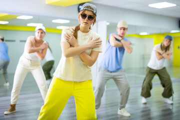 Teenager girl in cap dances hip hop dances in dance studio