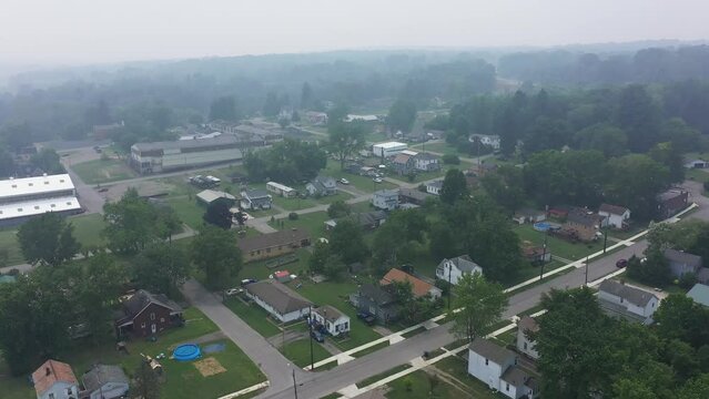 A daytime aerial view of the little industrial town of Masury, Ohio. Factories in the distance. Foggy view due to the Canadian wildfires of 2023.  	