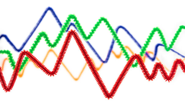 Market trends, inflation and fluctuations. Up and down line graphs created from colorful pipe cleaners. Red, green blue, and orange. Isolated on white. Shallow depth of field.
