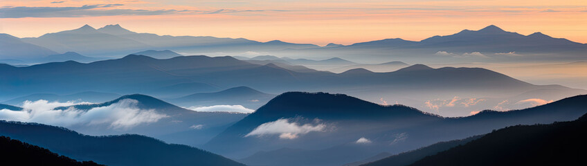 Mountain ridges covered with a forest shrouded in dawn- kissed clouds
