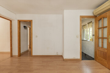 Living room of an empty apartment with pine wood doors leading to other rooms