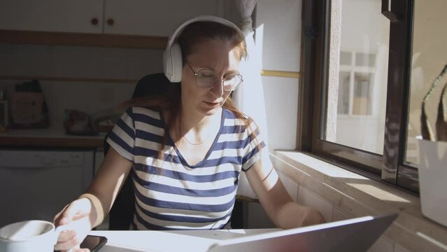 Adult woman works at loptop at home, drink coffee