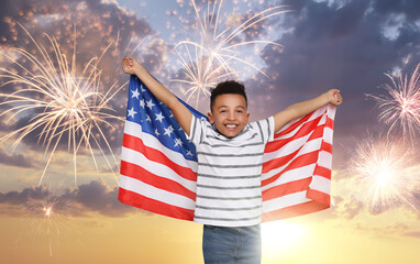 4th of July - Independence day of America. Happy kid holding national flag of United States against sky with fireworks