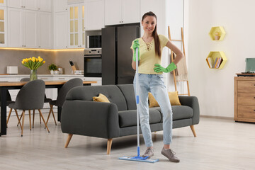 Fototapeta premium Spring cleaning. Young woman with mop washing floor at home