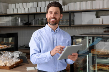 Happy business owner with tablet in bakery shop