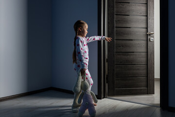 Girl in pajamas with toy bunny sleepwalking indoors at night