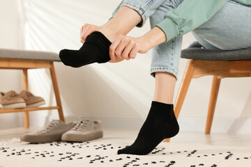 Woman putting on black socks at home, closeup