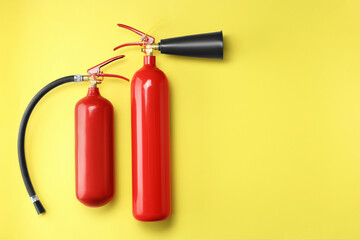 Obraz premium Fire extinguishers on yellow background, flat lay. Space for text