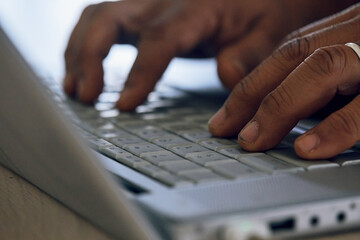 close up of fingers typing on silver laptop keyboard selective focus