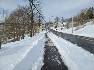 A cleared road and sidewalk after a winter storm.