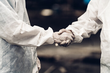 Scientist wear Chemical protection suit shaking hands.  Scientist working at dangerous zone