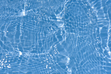 Blue water with ripples on the surface. Defocus blurred transparent blue colored clear calm water surface texture with splashes and bubbles. Water waves with shining pattern texture background.
