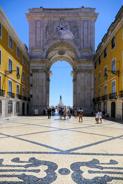 Encantadora rua de Lisboa em um dia ensolarado, finalizada pelo majestoso Arco do Triunfo e em destaque o deslumbrante cal&ccedil;amento de pedras formando mosaicos encantadores.