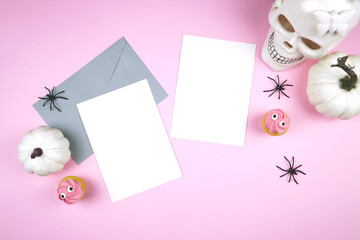 Pink Halloween two 5x7 greeting card, party invitation mockup. Trick or treat party supplies stationery styled with white skull, pumpkins, black spiders, and spooky cupcakes. Negative copy space.