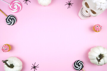 Fototapeta na wymiar Pink Halloween framed border background backdrop. Trick or treat party styled with white skull, pumpkins, black spiders, and spooky cupcakes. Negative copy space.
