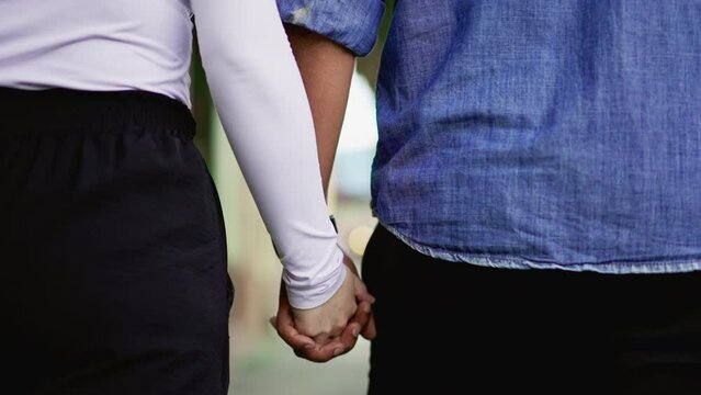 Romantic couple holding hands walking outside in street, close-up of person hands held together in marriage partnership